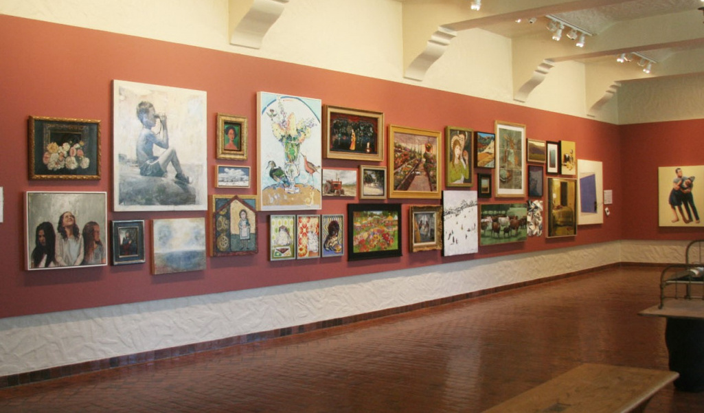 Photo of red gallery wall covered in a large variety of paintings