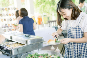 Smiling girl in a buffet line putting salad onto her plate