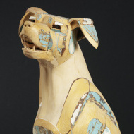 light-colored wood sculpture of a dog's face and neck