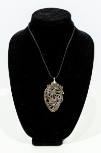black jewelry display with an abstract metal necklace displayed on it